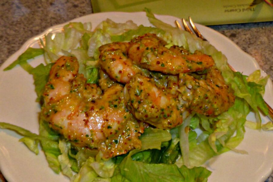 Reheated crawfish tails coated with garlic butter and Cajun seasoning, garnished with lemon wedges and parsley, served with a flavorful shell broth.