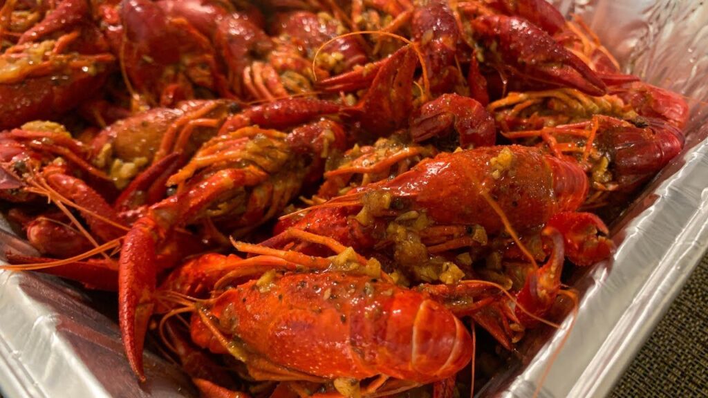 A platter of perfectly reheated frozen cooked crawfish, garnished with lemon wedges, fresh parsley, and Cajun spices, ready to be served in a seafood meal or recipe.
