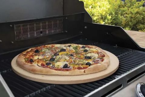 Homemade pizza cooking on a Blackstone griddle outdoors, with a golden crust and melted cheese. The flat surface distributes heat evenly, while a dome lid and oil help prevent sticking and ensure restaurant-style results.